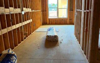 Rolls of fiberglass batt insulation in a framed hallway.