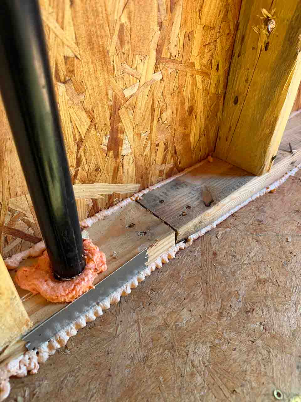Spray foam sealant air sealing a pipe penetration at the bottom plate in a new construction DRB Homes home in Stockbridge, GA by Foster Insulation.