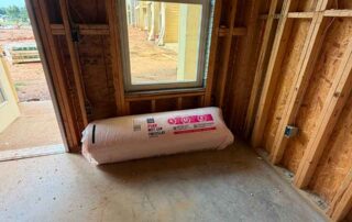 Roll of Owens Corning PINK Next Gen Fiberglas batt insulation staged near a doorway in a framed unit at the Accent Marietta apartment complex in Marietta, GA.