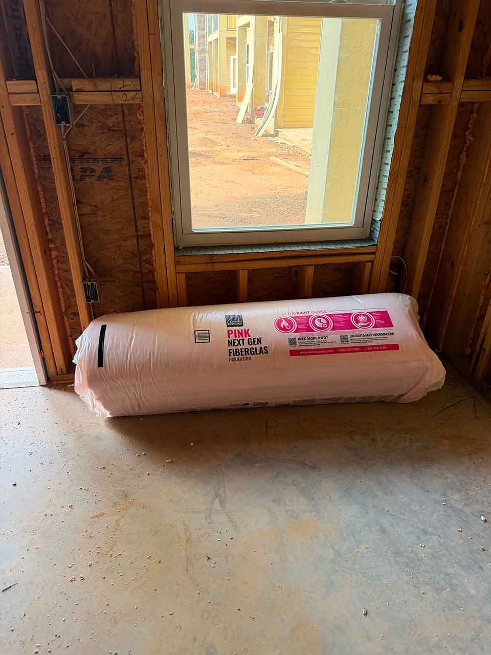 Roll of Owens Corning PINK Next Gen Fiberglas batt insulation staged inside a framed unit at the Accent Marietta apartment complex.
