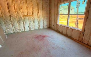 Fiberglass batt wall insulation installed in a framed room with a window view.