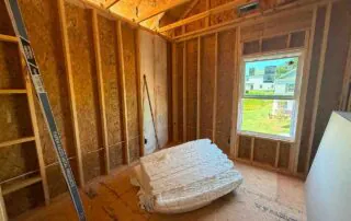 Unbagged fiberglass batt insulation staged on the subfloor in a framed room at Kingston Park in Kingston, GA for Smith Douglas Homes.