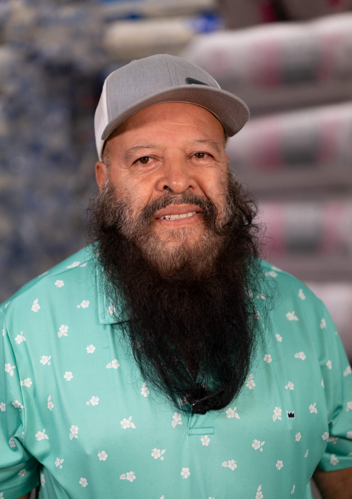 Estreberto Estreberto wearing a light green floral shirt and gray cap, smiling with a background of insulation materials