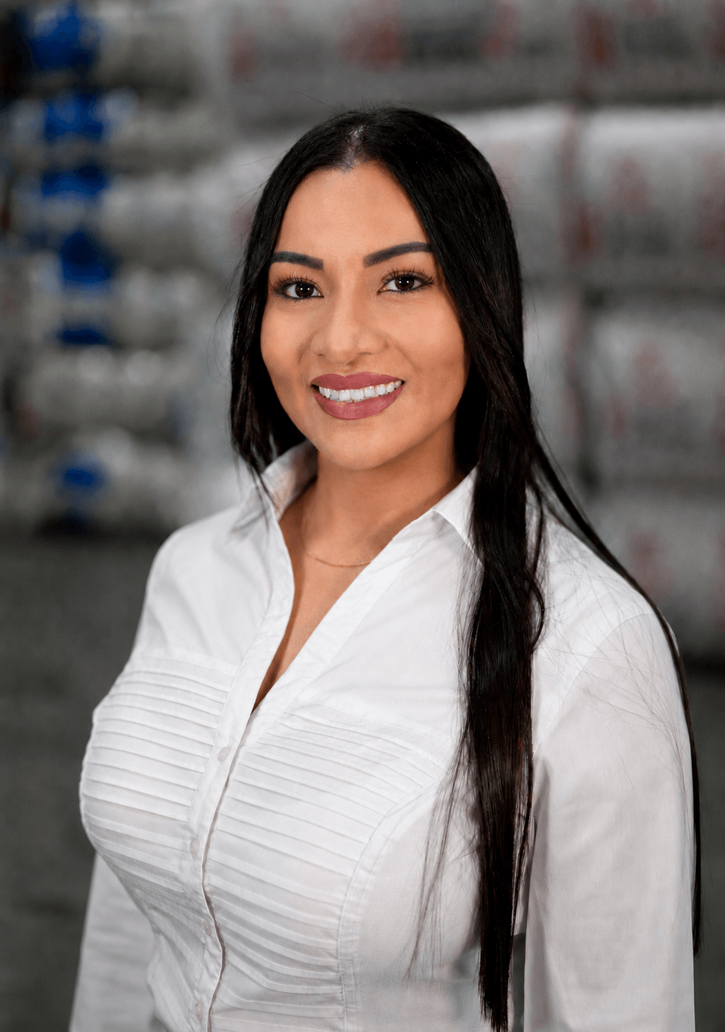 Lady Penuala Lady Penuala smiles in a white blouse, standing in front of stacked insulation materials at Foster Insulation