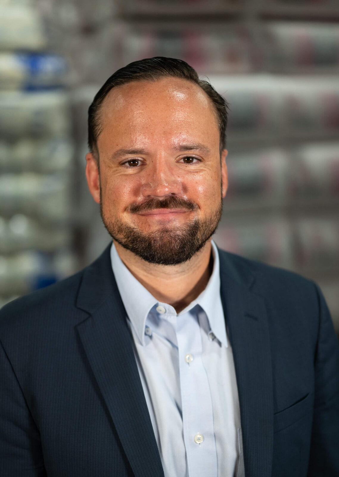 Patrick Morris smiling in a business suit against a blurred background, conveying a professional appearance