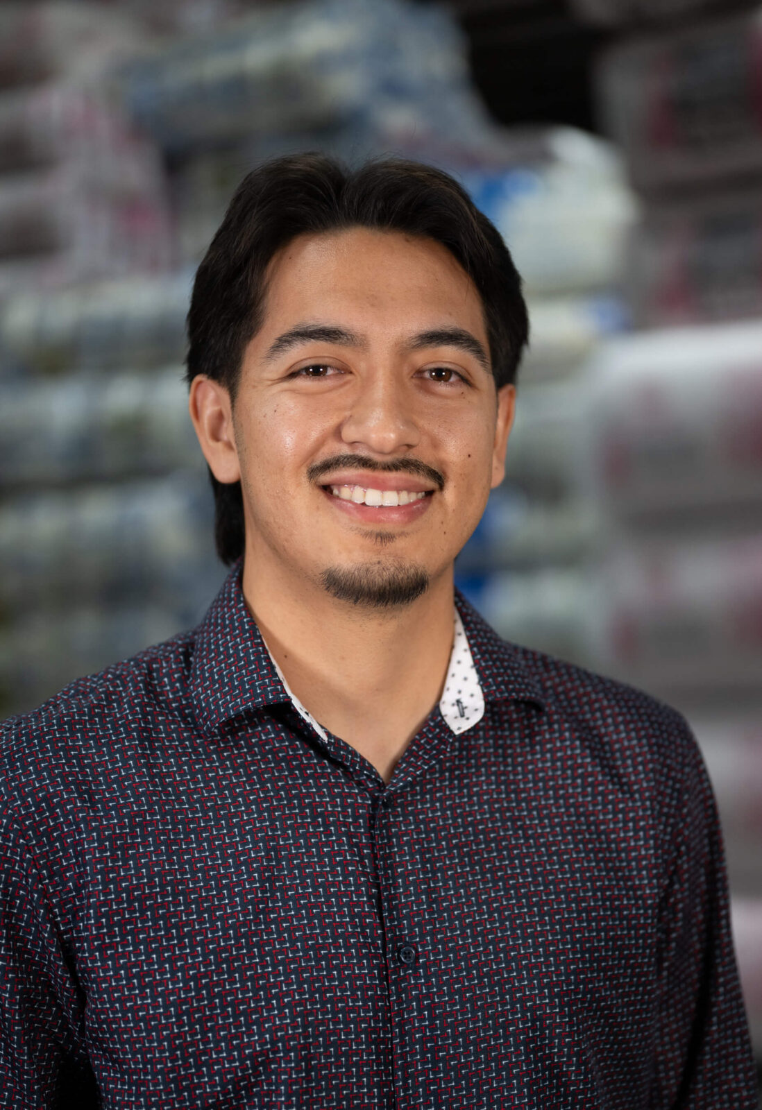 Saul Torres Saul Torres smiling indoors, wearing a patterned shirt with a warehouse background