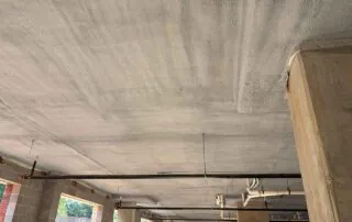 Closed-cell spray foam coating a parking deck ceiling bay near a support column in Fulton County, GA.