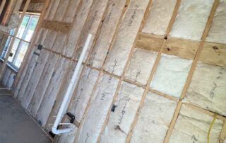 Foster Insulation R-20 fiberglass batt insulation installed in a long exterior wood stud wall of a home under construction.