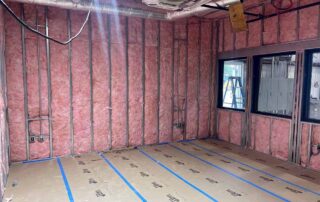 Fiberglass batt insulation installed in walls and ceiling in a room of a residential remodel.