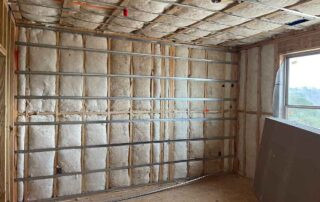 Foster Insulation fiberglass batt insulation installed in the walls and ceiling of a room with horizontal metal channels over the framing.