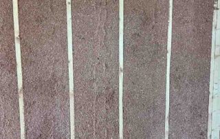 Spray-applied cellulose insulation packed flush with wood wall studs.