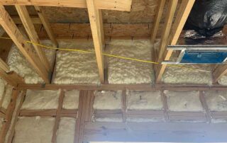 Spray foam insulation installed in ceiling above fiberglass batt insulation in walls during a residential remodel.